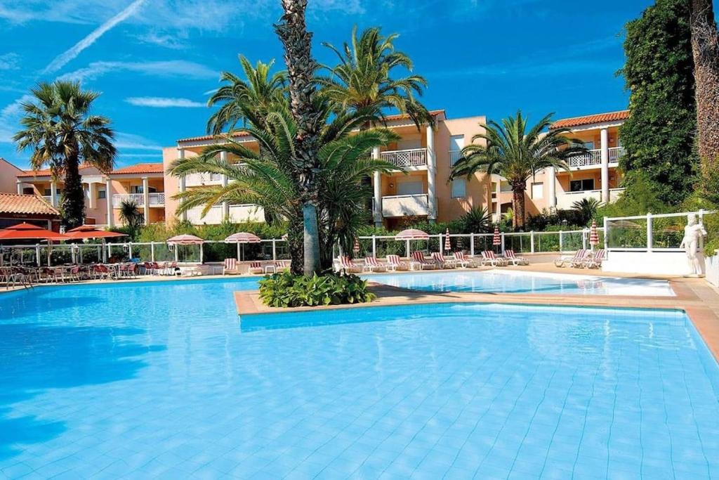 une grande piscine avec des palmiers et un bâtiment dans l'établissement GOLFE JUAN, Cosy T3 , piscine , parking, au Golfe-Juan