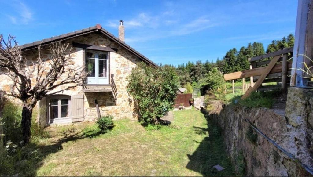a stone house with a garden and a fence at La Coquette du Bois - Wifi, Cosy, Familial, Calme, Bord de forêt in Chenereilles