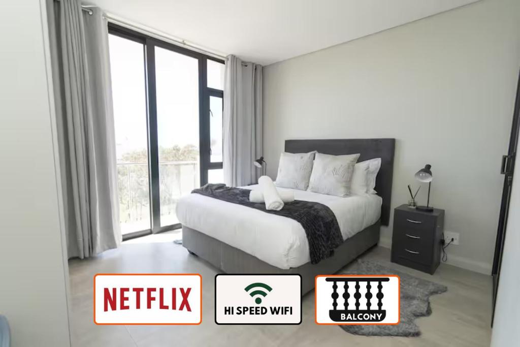 una camera da letto bianca con un letto e una finestra di Boardwalk Bungalow a Gqeberha