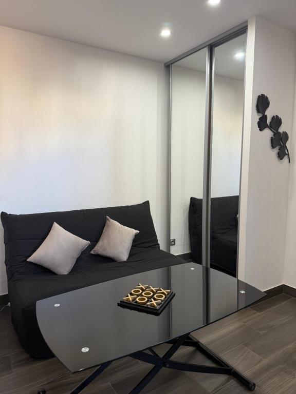 - un salon avec un canapé noir et une table en verre dans l'établissement Studio, Maison, rez de chaussée, Perpignan, à Perpignan