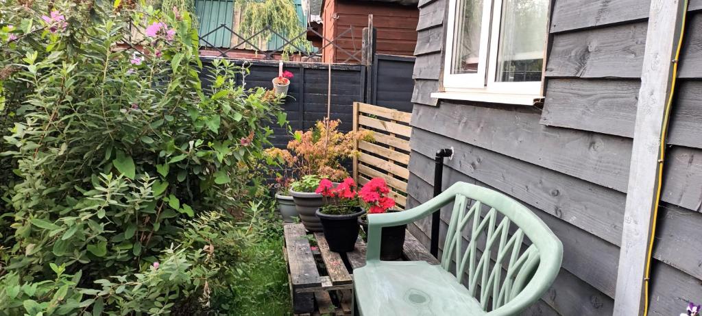 a green bench sitting next to a house with plants at Robins nest in Great Hanwood