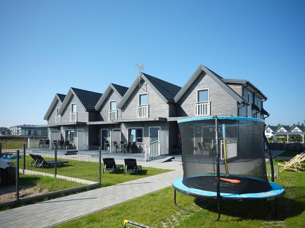 a house with a trampoline in the yard at Baltic Domki Sarbinowo in Sarbinowo