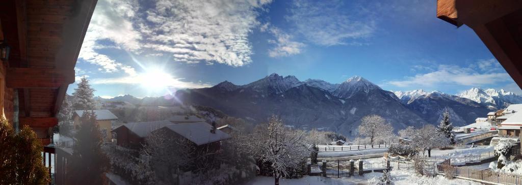 einen Blick auf eine verschneite Bergkette mit der Sonne am Himmel in der Unterkunft Les Vrais Rayons in Verrayes