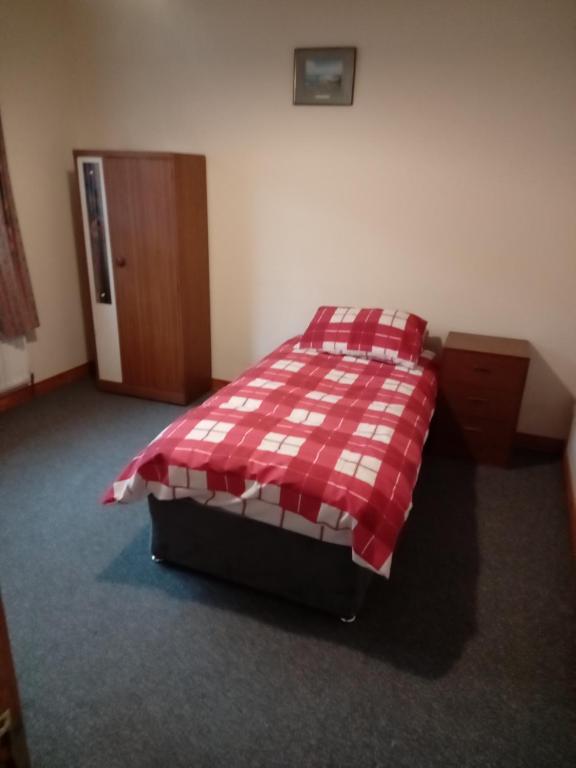a bed in a room with a red and white blanket at Causeway holiday home in Ballycastle