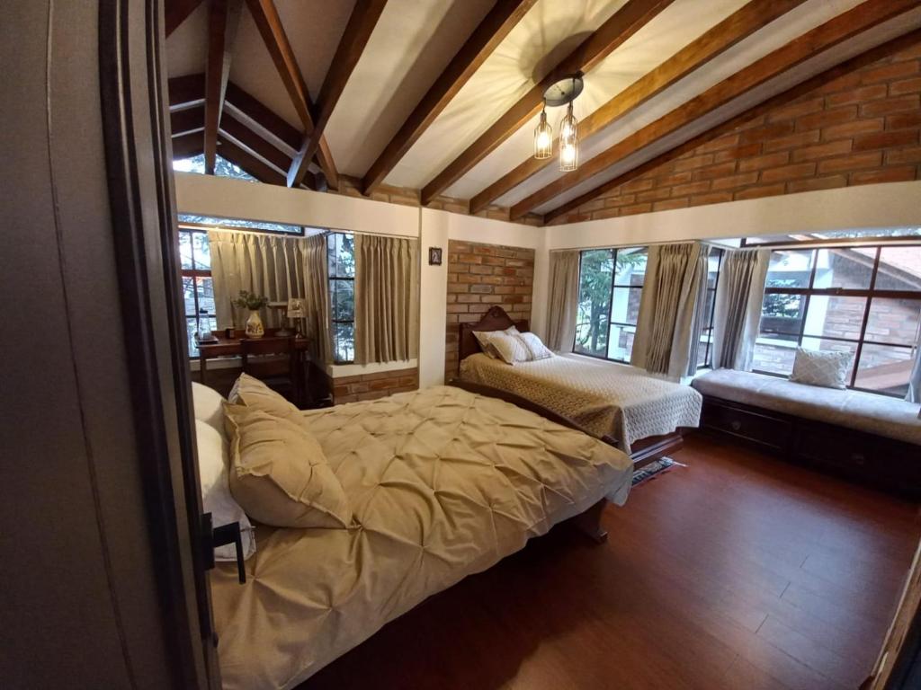 a bedroom with a bed and a couch and windows at La Posada del Chagra HOST in Machachi