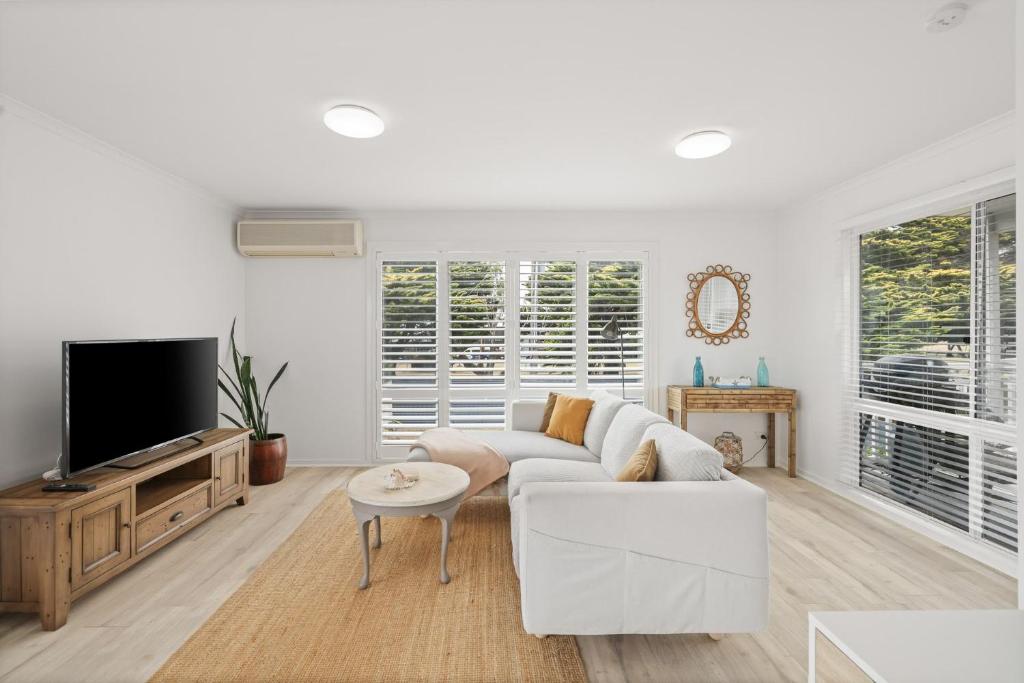 a living room with a white couch and a tv at Cerulean Getaway in Cowes