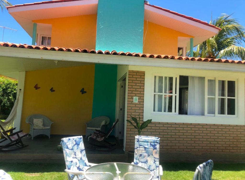 una casa colorata con tavolo e sedie di Casa de praia condomínio beira-mar praia de sonho verde alagoas n 9 a Paripueira