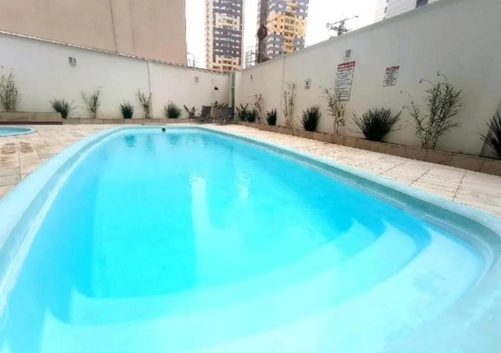 a swimming pool with blue water in a building at Lindo Apartamento na Praia de Itapuã - Vila Velha -com ar condicionado na 2 quadra do mar ES in Vila Velha