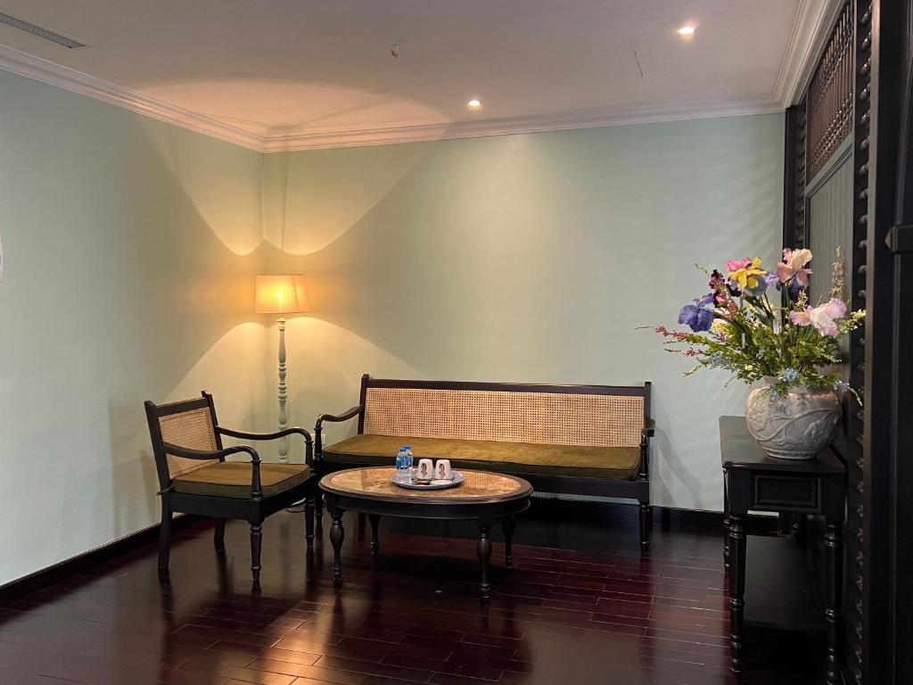 a living room with a bench and a table and flowers at Homestay Art Bát Tràng in Kim Quan