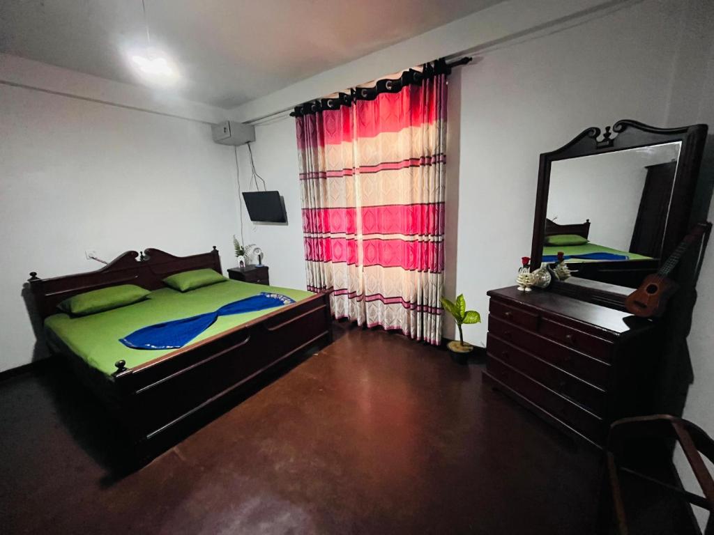 a bedroom with a bed and a mirror and a dresser at Lavender Apartment Welimada in Ambagasdowa