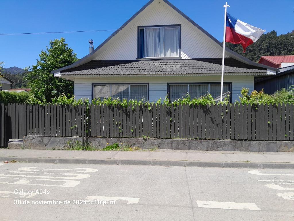 a house with a flag in front of a fence at Casa Florecer in Contulmo