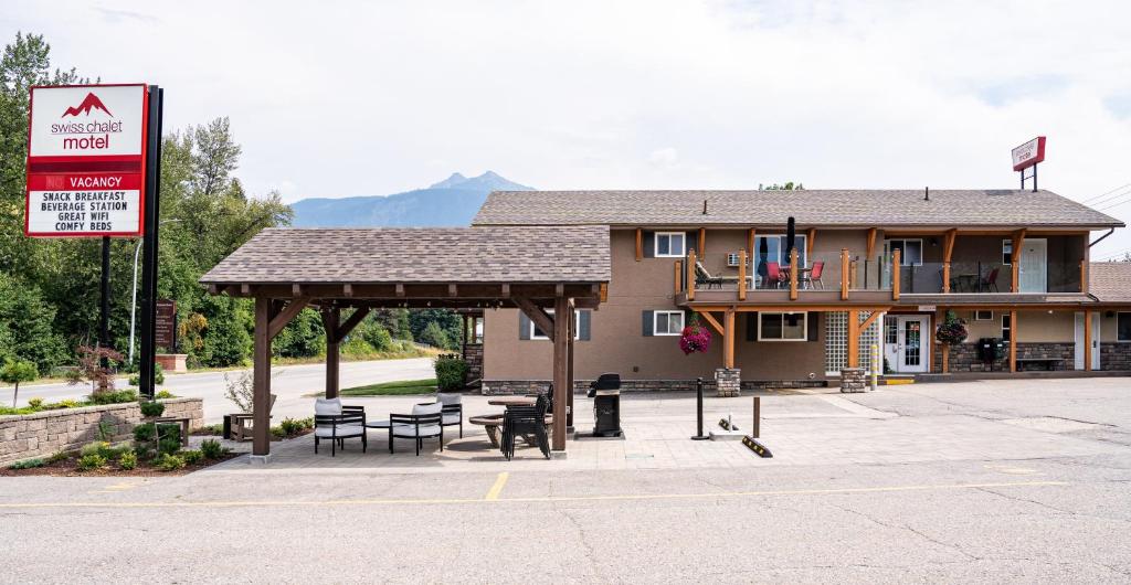 a building with a pavilion with tables and chairs at Swiss Chalet Motel in Revelstoke