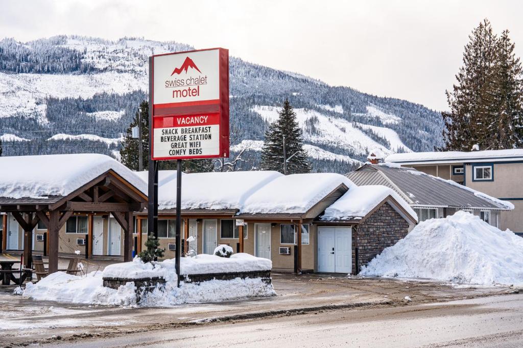 a sign in front of a snow covered hotel at Swiss Chalet Motel in Revelstoke