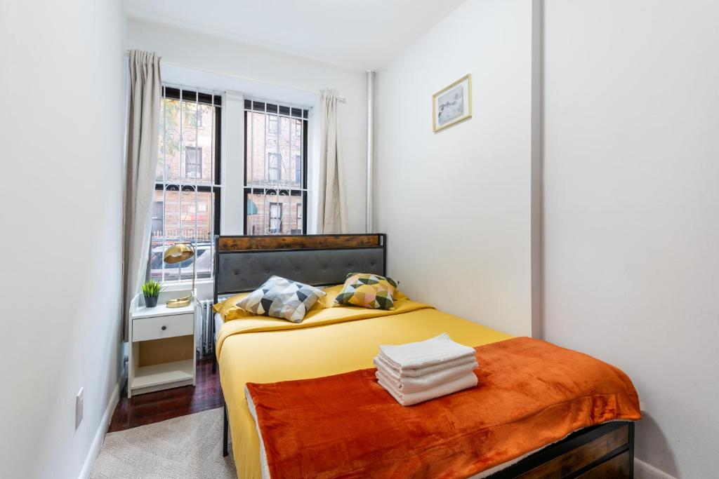 a bedroom with a yellow bed and a window at 2 BD Cozy Home in Manhattan Valley in New York