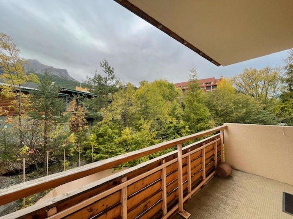 - un balcon avec vue sur les arbres et un bâtiment dans l'établissement Studio confortable 4 pers, accès pistes, terrasse - FR-1-804-48, à Enchastrayes