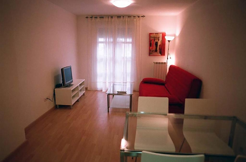 ein Wohnzimmer mit einem roten Stuhl und einem TV in der Unterkunft Apartamentos Auhabitat Zaragoza, edificio de apartamentos turísticos in Saragossa