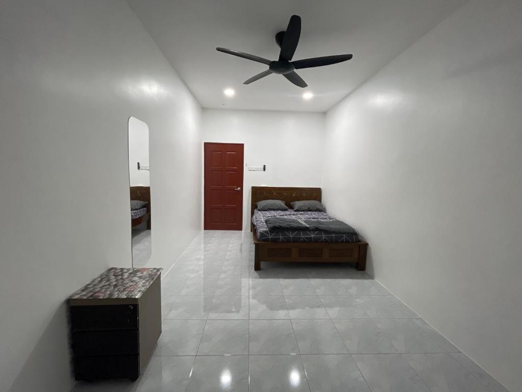 Un dormitorio con una cama y un ventilador de techo. en Dhaya Homestay, en Kuantan