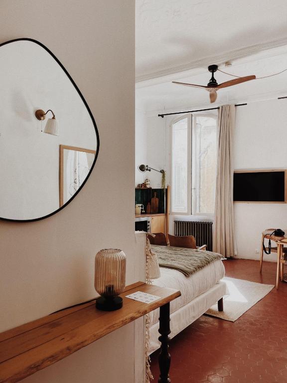 une chambre avec un lit et un miroir au mur dans l'établissement Maison Acacia - La bibliothèque, à La Ciotat