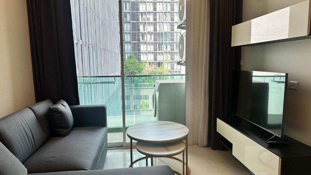 a living room with a couch and a television and a table at Spacious Sukhumvit Condo near EmQuartier in Bangkok