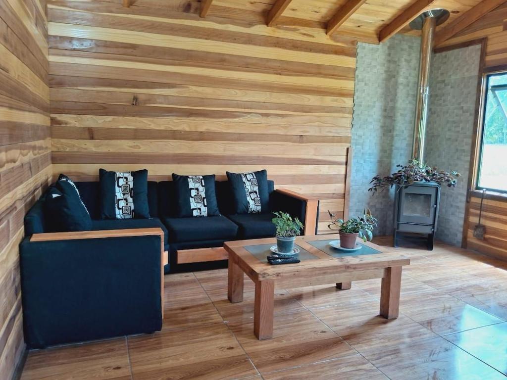 a living room with a black couch and a table at Arriendo Diario de Cabaña en Villarrica in Voipire