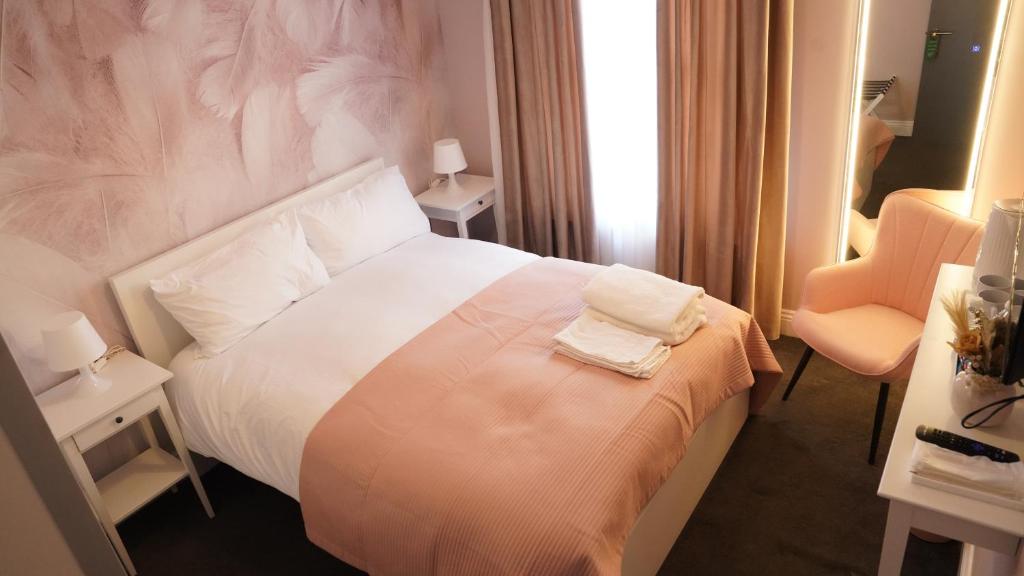 a hotel room with a white bed and a chair at Mandeville Guest House in Enfield Lock
