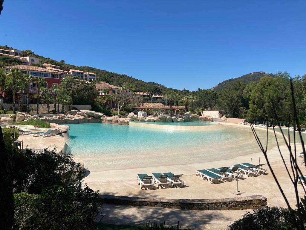 una piscina con sedie a sdraio e una spiaggia di Appartement Restanques du Golf de Saint Tropez 2 chambres 6 personnes a Grimaud