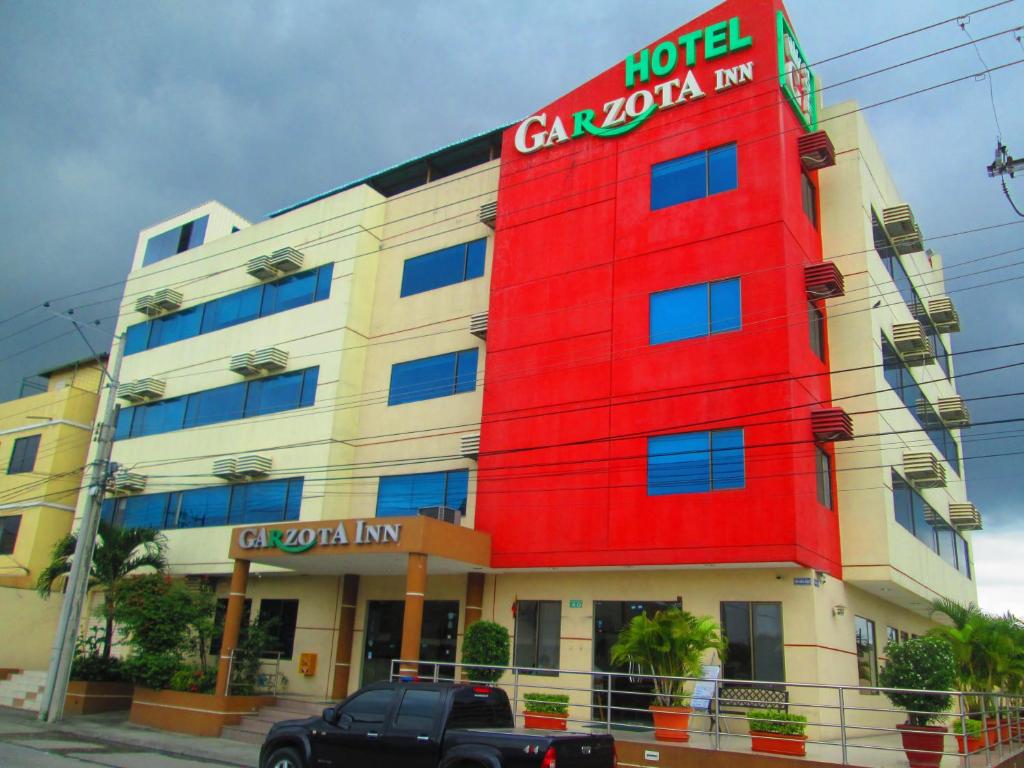 un edificio rojo con un camión estacionado frente a él en Hotel Garzota Inn, en Guayaquil