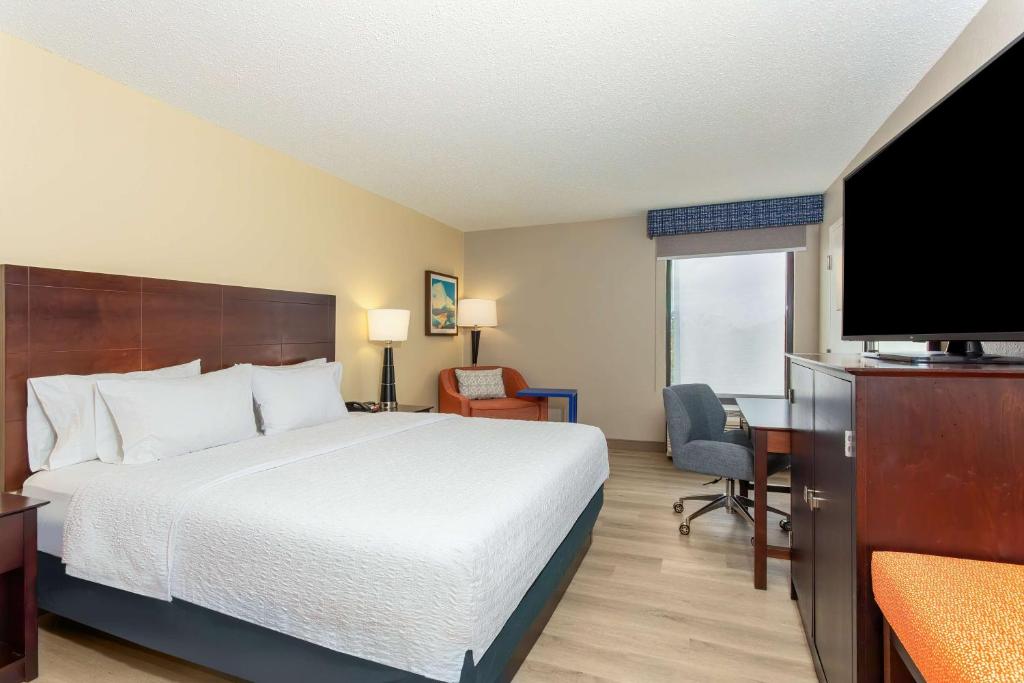 a hotel room with a bed and a flat screen tv at Hampton Inn Orlando-International Airport in Orlando