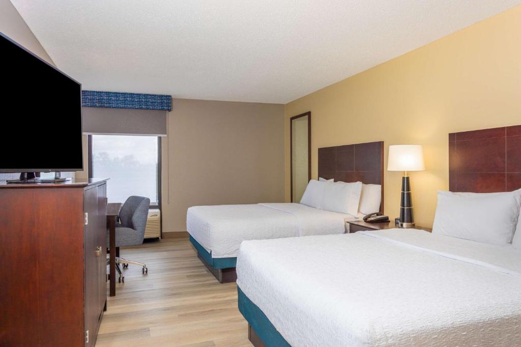 a hotel room with two beds and a flat screen tv at Hampton Inn Orlando-International Airport in Orlando