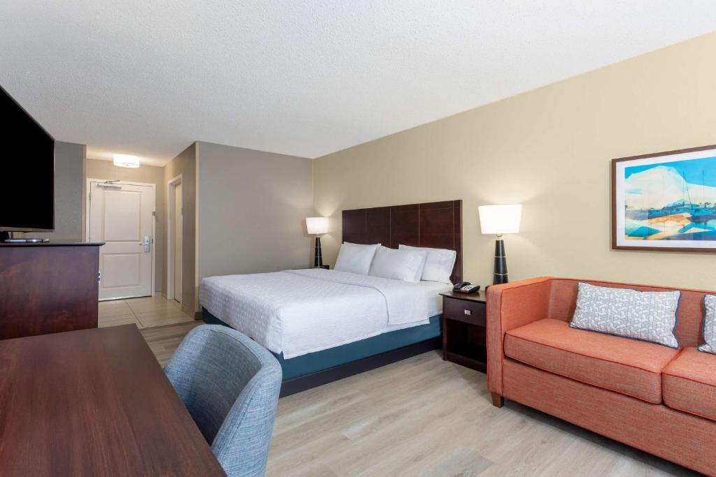 a hotel room with a bed and a couch at Hampton Inn Orlando-International Airport in Orlando