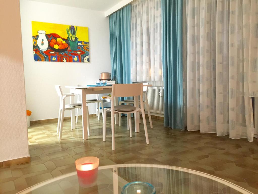 a living room with a table and chairs and a painting at Ferienwohnung Südpark Apartment - Bad Nauheim in Bad Nauheim