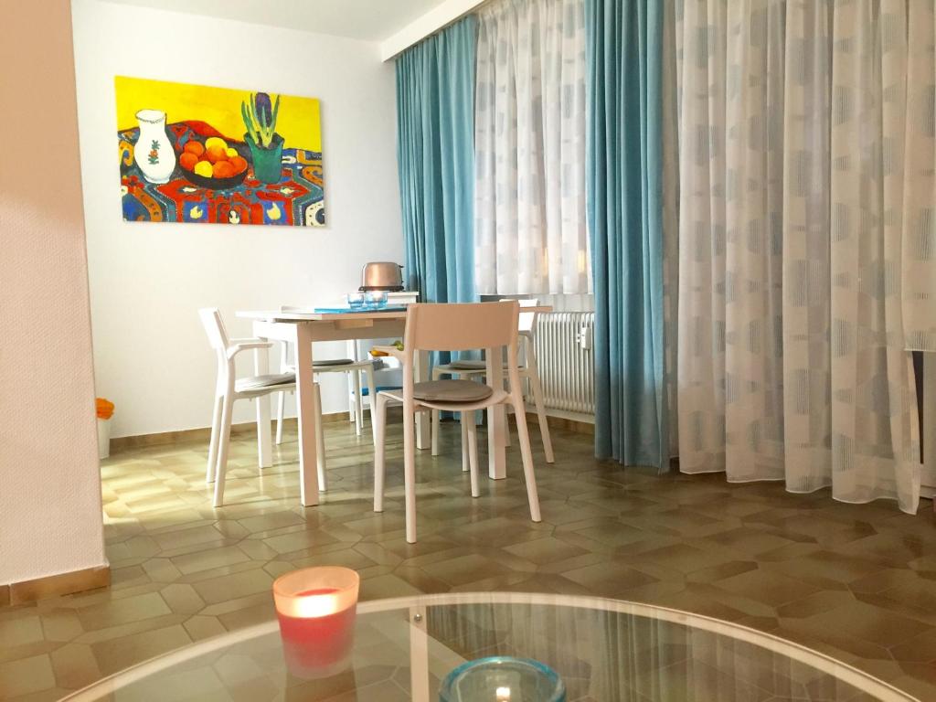 ein Wohnzimmer mit einem Tisch, Stühlen und einem Gemälde in der Unterkunft Ferienwohnung Südpark Apartment - Bad Nauheim in Bad Nauheim