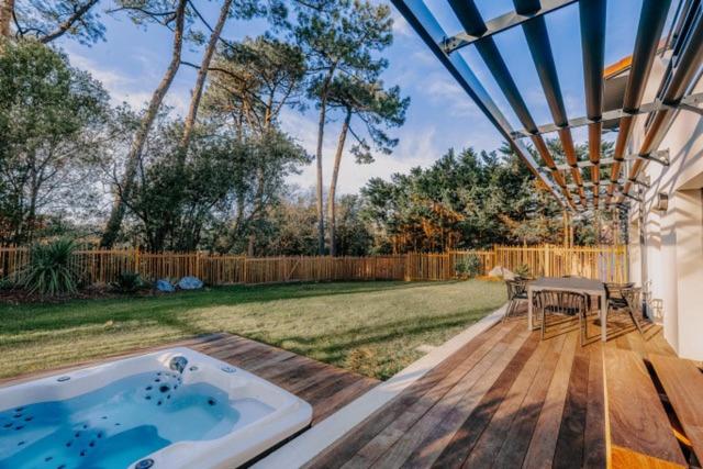 un bain à remous sur une terrasse en bois avec une arrière-cour dans l'établissement Appartement avec Jacuzzi spacieux et lumineux au cœur de Chiberta, à Anglet