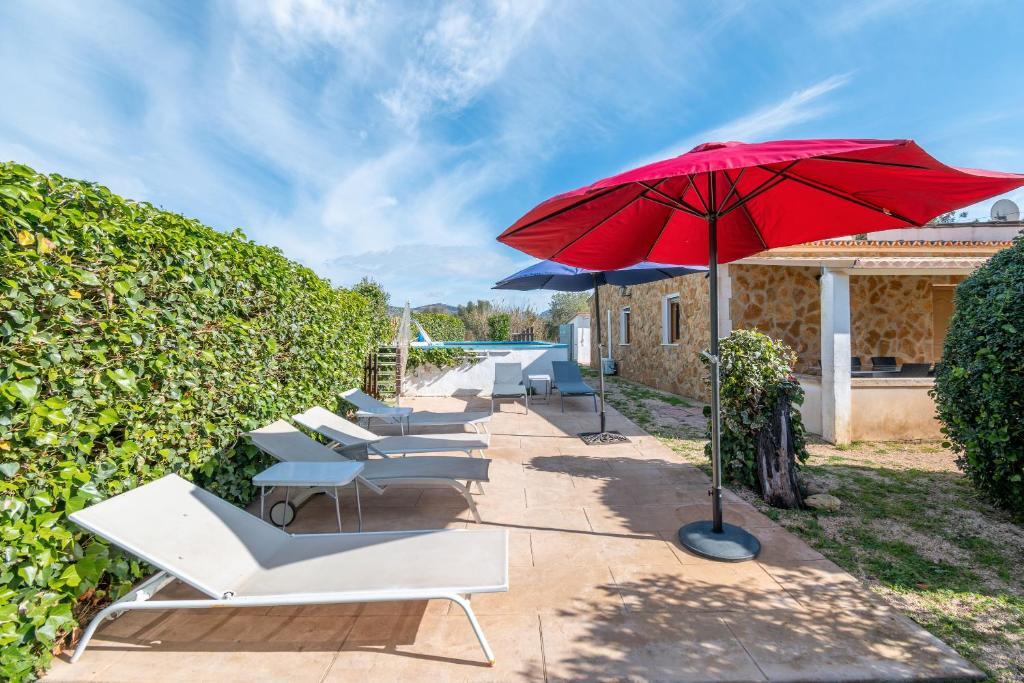 a row of white chairs and a red umbrella at Es Marroig Villa y Spa in Llucmajor