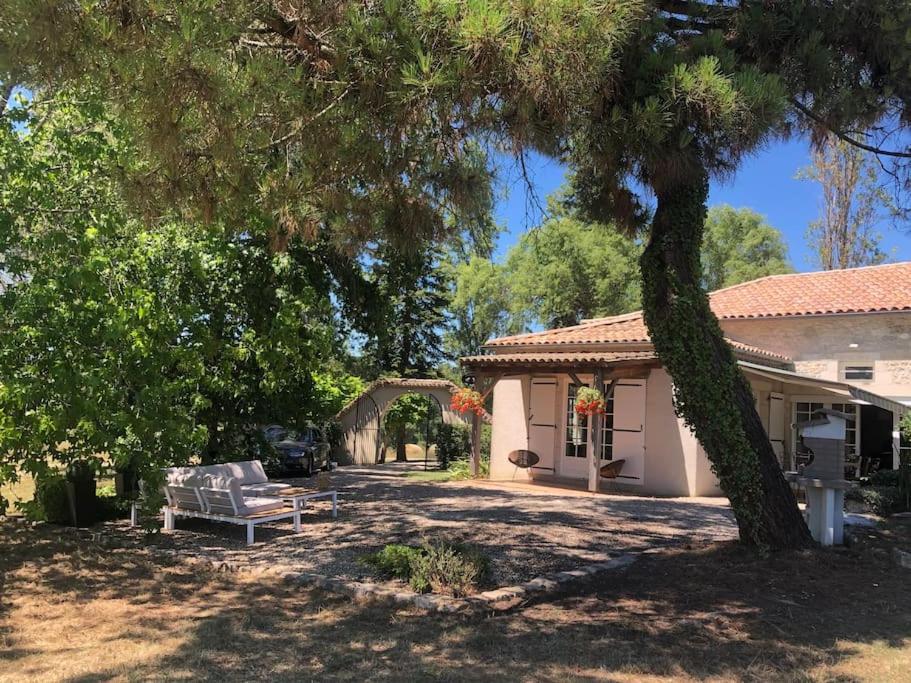 un banc devant une maison avec un arbre dans l'établissement Charmant gîte de 4 à 6 personnes à 5km de Duras, à Savignac-de-Duras