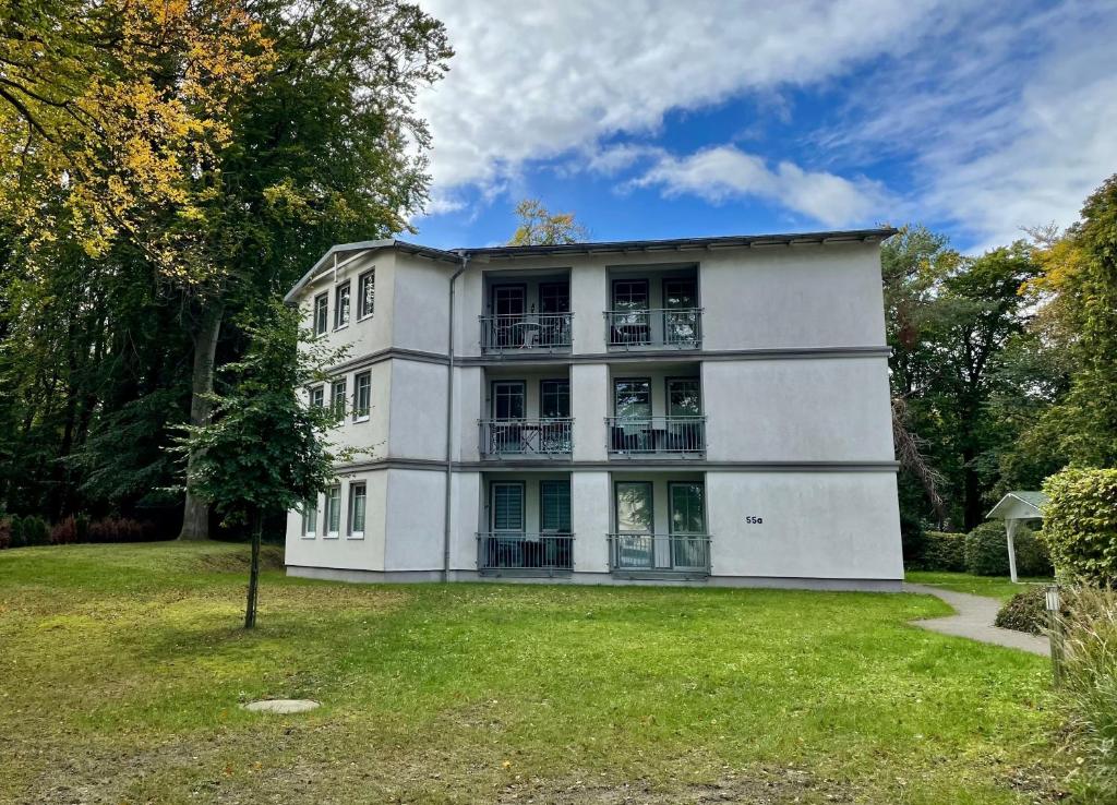 un ancien bâtiment blanc avec une cour d'herbe dans l'établissement Haus am Buchenpark 09, à Neuhof