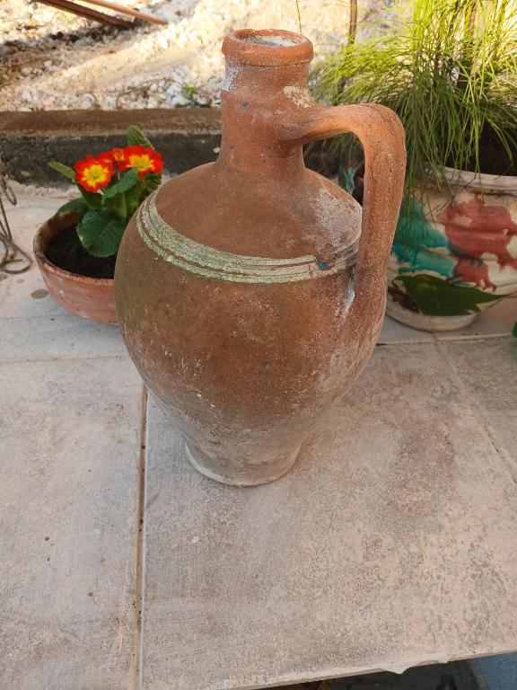 an old vase sitting on the ground next to some plants at Athina in Thessaloniki
