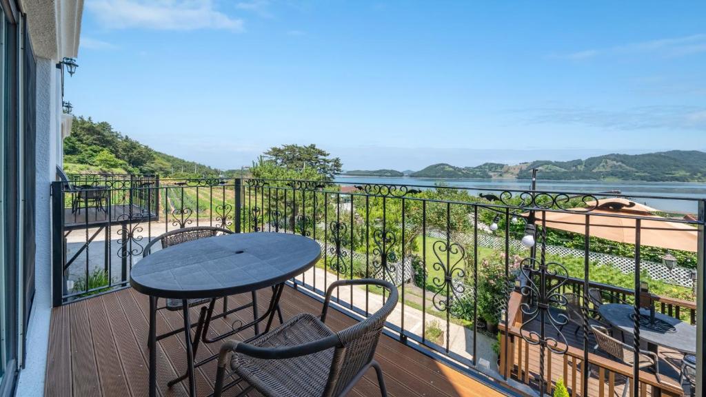 a balcony with a table and chairs and a view of the water at Namhae Ryu&Lee Pet Pension in Namhae