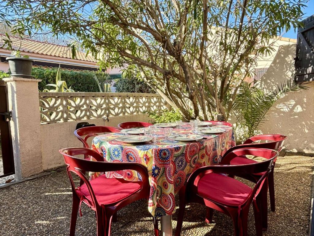 - une table avec des chaises rouges et une table avec de la vaisselle dans l'établissement Maison 3 pièces mezzanine 6 couchages ARGELES SUR MER AR610-058, à Argelès-sur-Mer