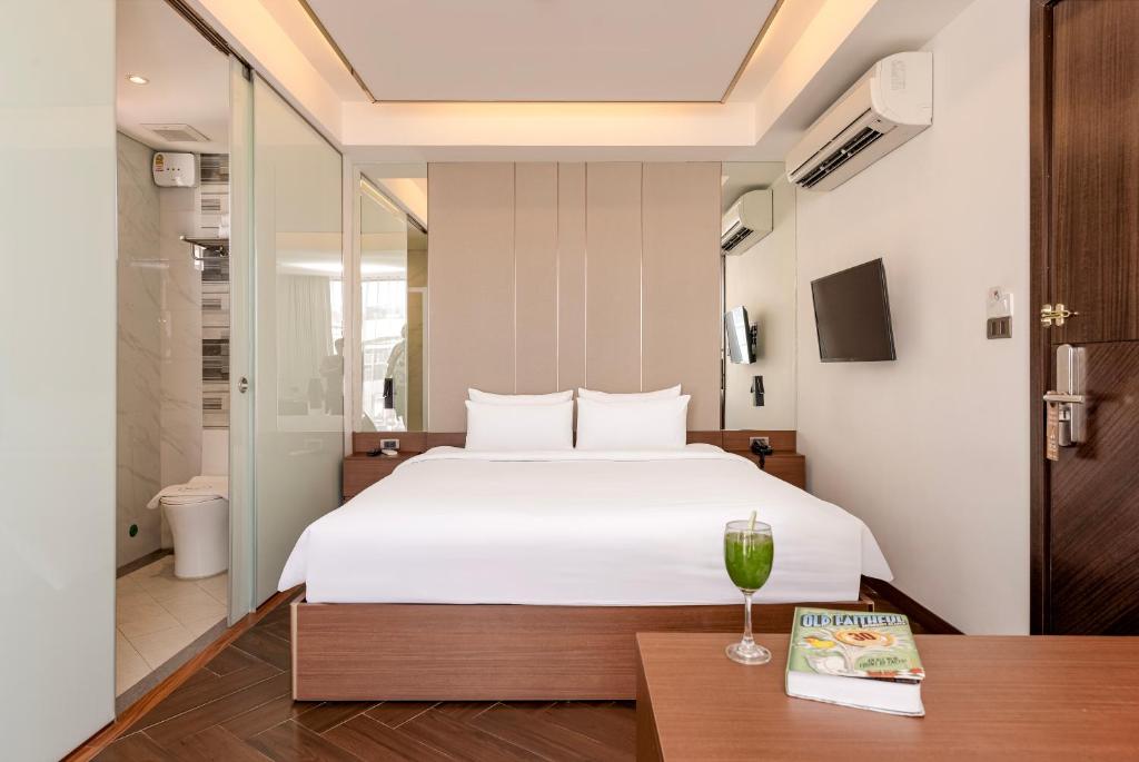 Schlafzimmer mit einem Bett und einem Tisch mit einem Glas Wein in der Unterkunft Riverside Hotel in Vientiane