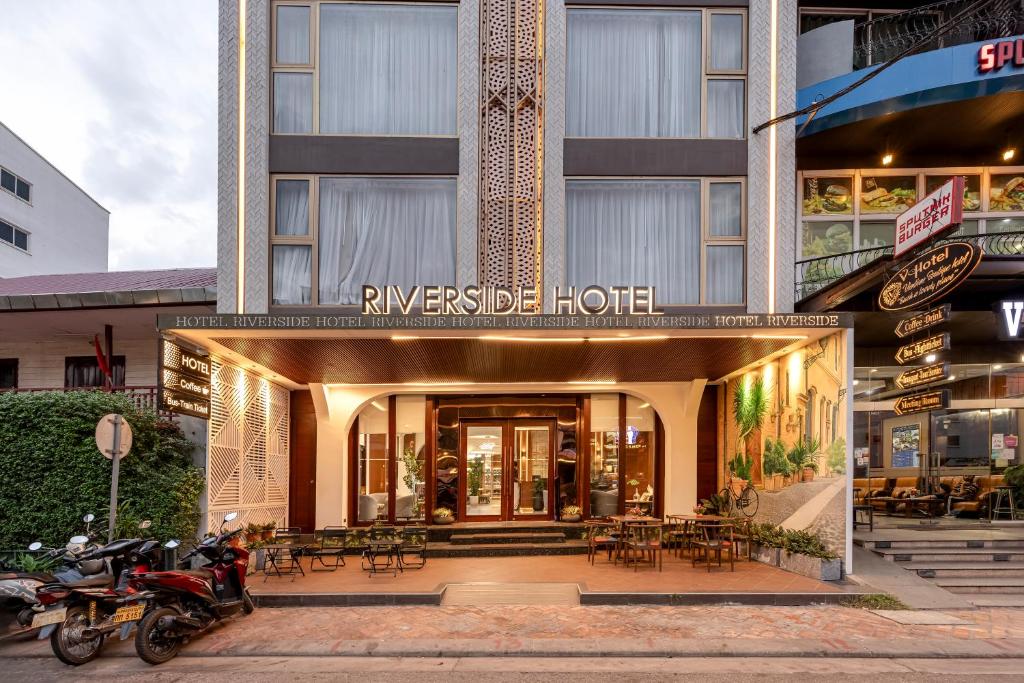 ein Hotel mit Motorrädern, die außerhalb eines Gebäudes geparkt sind in der Unterkunft Riverside Hotel in Vientiane