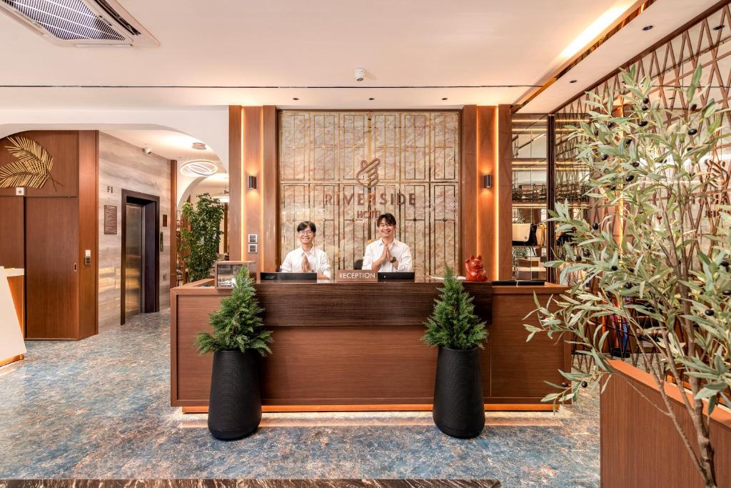 zwei Personen stehen an einer Theke in einem Restaurant in der Unterkunft Riverside Hotel in Vientiane