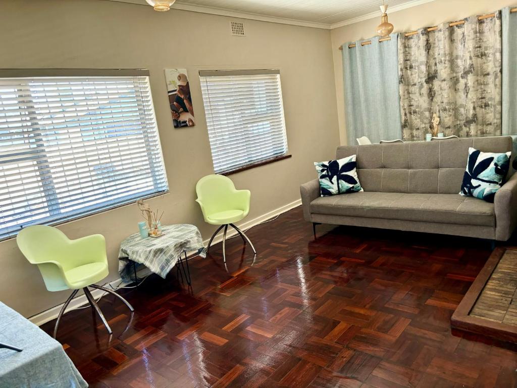 Una sala de estar con un sofá, una mesa y sillas. en One Bedroom House, en Goodwood