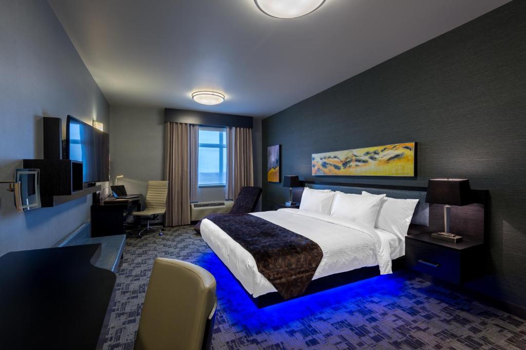 a hotel room with a large bed and a desk at Applause Hotel Calgary Airport by CLIQUE in Calgary