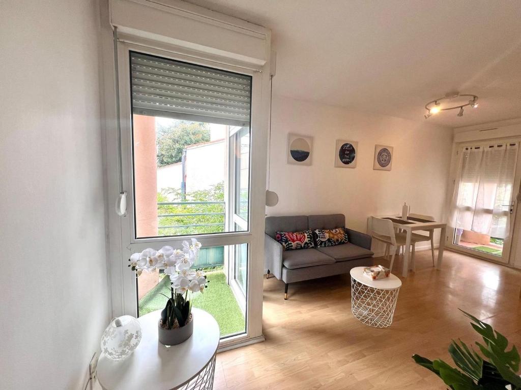 ein Wohnzimmer mit Couch und großem Fenster in der Unterkunft Charming T1 - Parking - Metro St Agne in Toulouse