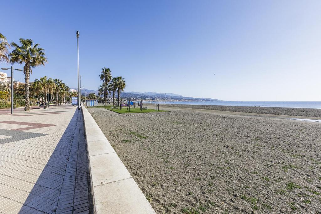 a sandy beach with palm trees and a sidewalk at A&N Sunny Stay in Torre del Mar Walk to the Beach in Torre del Mar