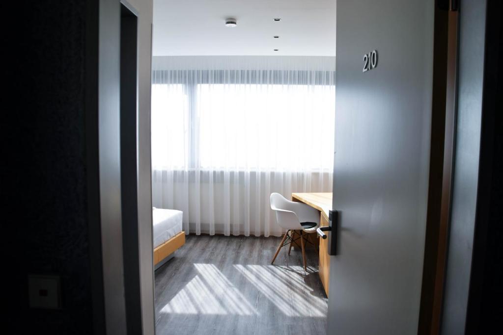 Cette chambre comprend un lit et un bureau avec une fenêtre. dans l'établissement Cristall Hotel, à Waghäusel