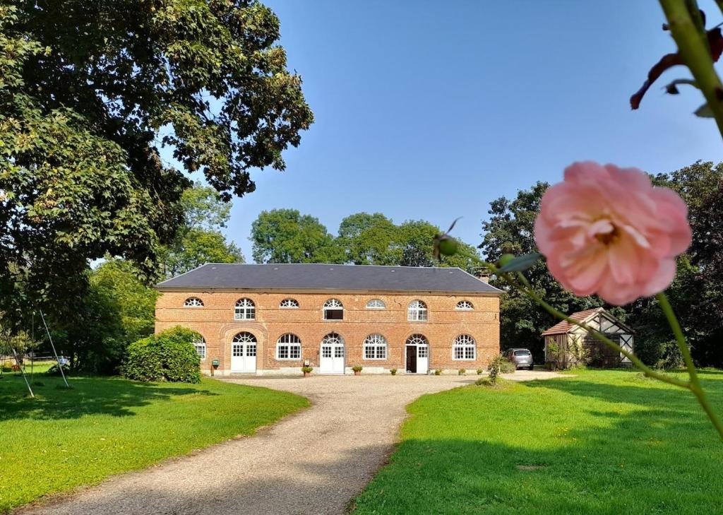un grand bâtiment en briques avec une fleur rose au premier plan dans l'établissement Les Ecuries du Château, à Gravigny