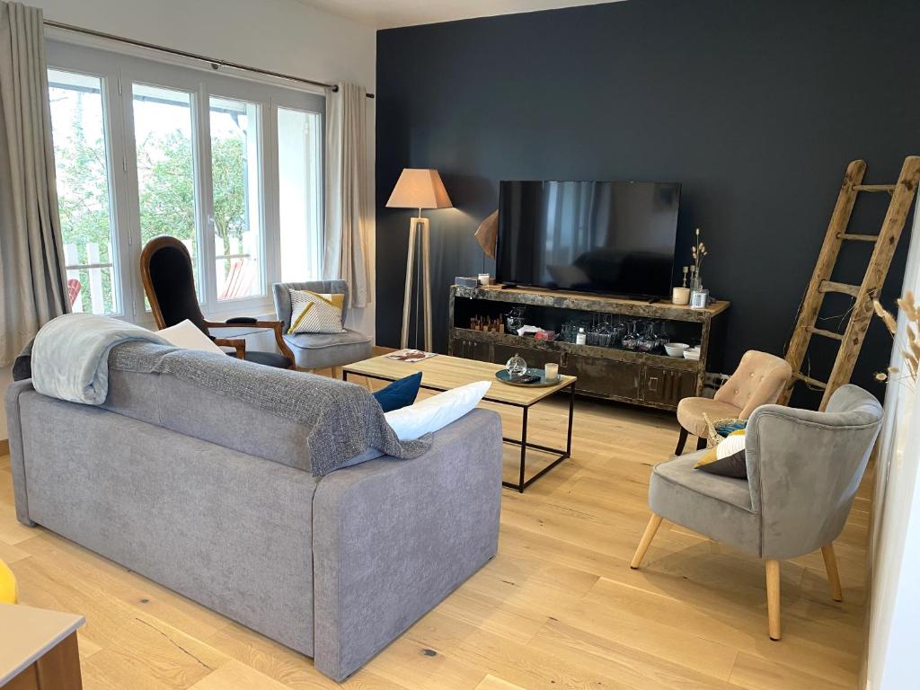 Il comprend un salon doté d'un canapé, de chaises et d'une télévision à écran plat. dans l'établissement Maison à 250m de la plage la Grève Blanche avec WIFI à TREGASTEL - Réf 182, à Trégastel