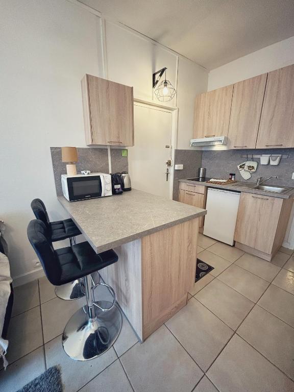 une cuisine avec des armoires en bois et un comptoir dans l'établissement Studio en plein coeur de Fontainebleau, château à 3 minutes à pieds, à Fontainebleau